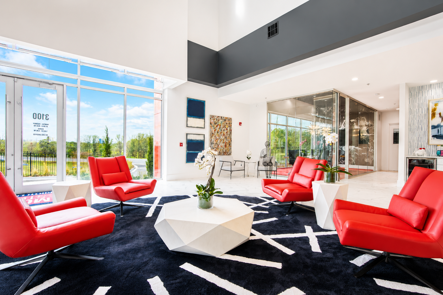 Modern office lobby at Modern Storage® North Little Rock featuring red lounge chairs, large windows, contemporary décor, and open seating areas.
